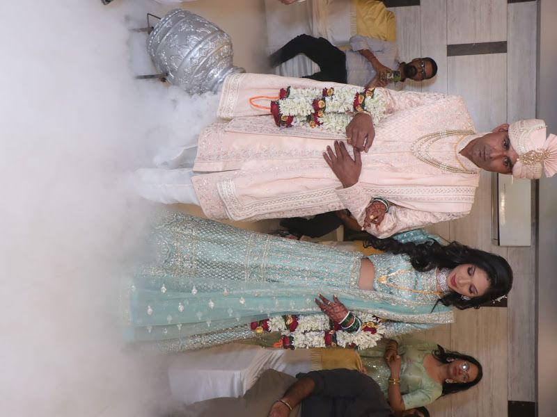 Wedding-entry moment — bride and groom in coordinated cream and powder-blue outfits making their entry through dry-ice fog — Arya Events Planner, Kharghar, Navi Mumbai