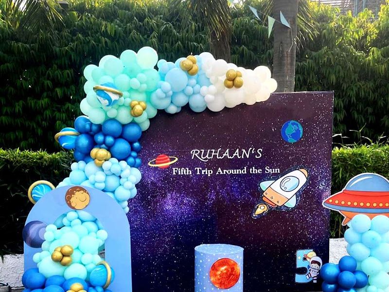 Space / astronaut theme ('Ruhaan's Fifth Trip Around the Sun') — blue balloon garland with planets, rocket and UFO cutouts on a starry backdrop — Arya Events Planner, Kharghar, Navi Mumbai