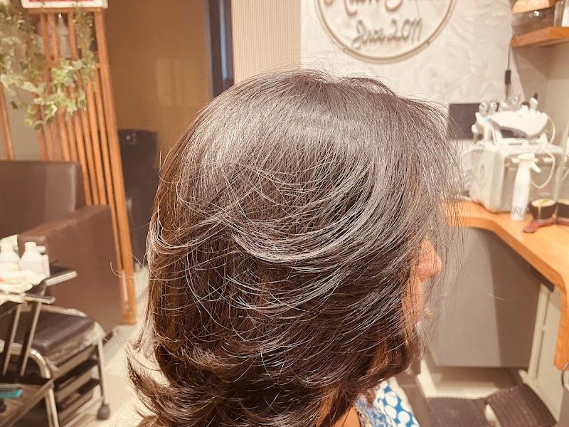 Salon interior with the etched 'The Rush Salon' mirror decal, styling stations and product shelving in the background. — The Rush Family Salon, Airoli, Navi Mumbai