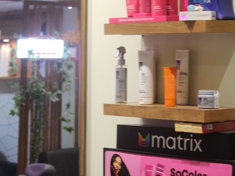 Matrix product wall — SoColor Pre-Bonded display and Matrix/professional styling products on wooden shelving beside a station mirror. — The Rush Family Salon, Airoli, Navi Mumbai
