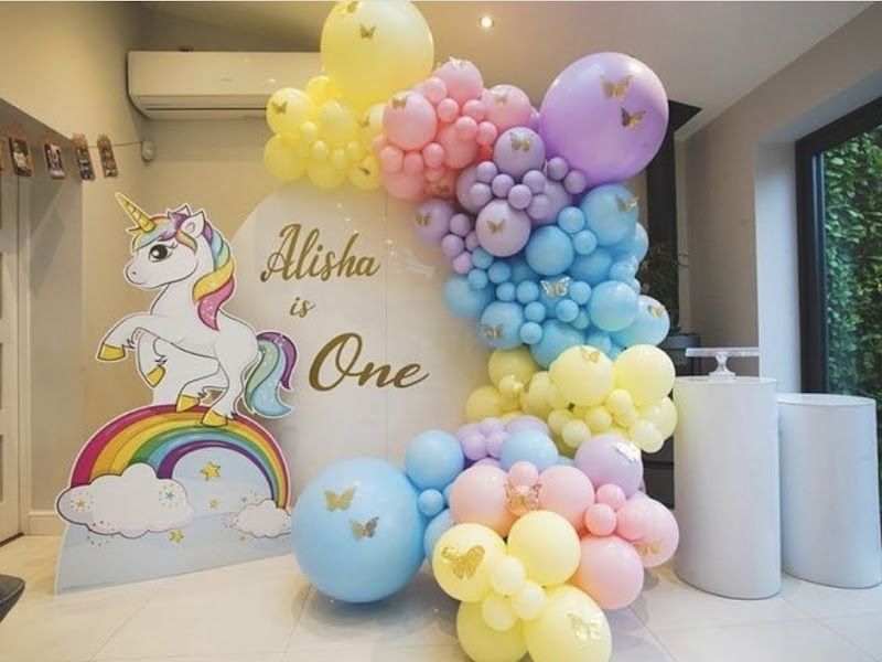 Unicorn-theme 1st birthday ('Alisha is One') — pastel rainbow balloon garland with a unicorn cutout and gold butterflies — Arya Events Planner, Kharghar, Navi Mumbai