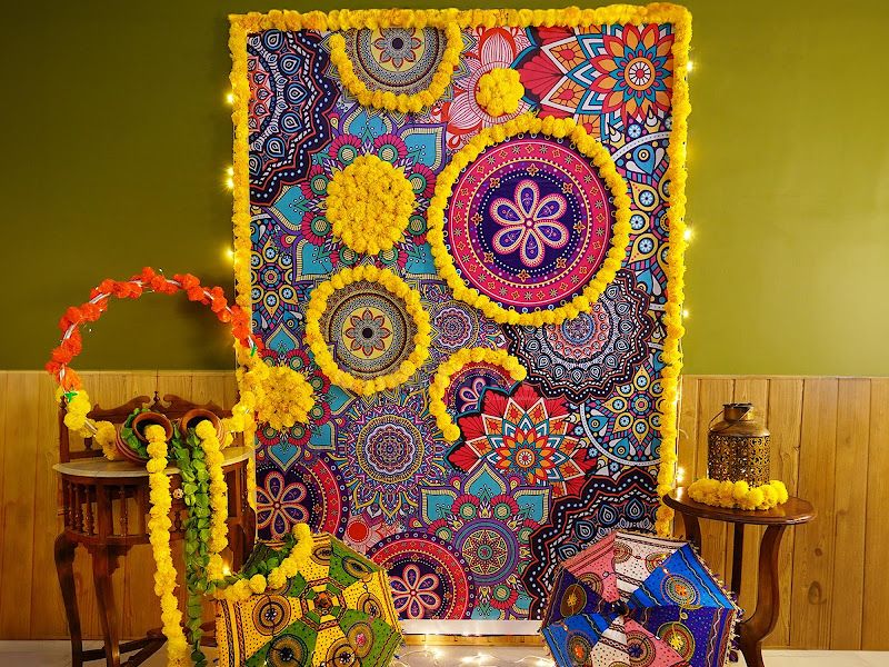 Ethnic mehndi / sangeet corner — vibrant mandala tapestry backdrop with marigold garlands, decorative umbrellas and fairy lights — Arya Events Planner, Kharghar, Navi Mumbai