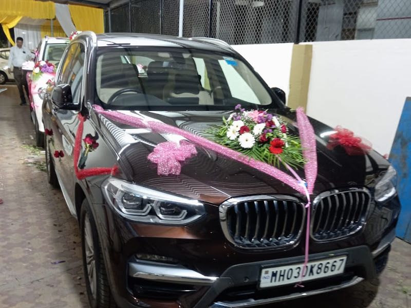 Wedding car decoration — maroon SUV dressed with pink-and-white florals and ribbon — Arya Events Planner, Kharghar, Navi Mumbai