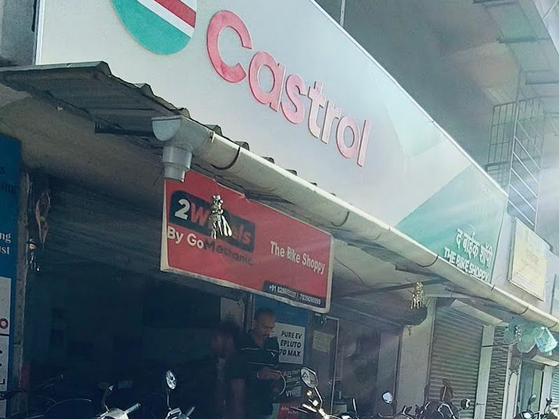 Portrait shopfront view under the Castrol board with scooters and bikes in front — The Bike Shoppy, Vashi, Navi Mumbai