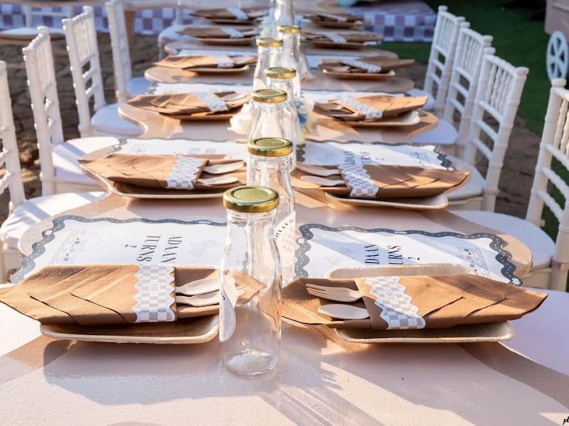 Catering tablescape — long table set with wooden plates, doily mats and lace-wrapped jars for an outdoor function — Arya Events Planner, Kharghar, Navi Mumbai