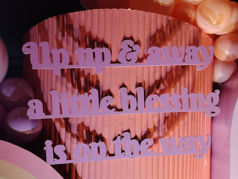 Baby-shower backdrop — pink fluted panel with 'Up up & away, a little blessing is on the way' lettering and pastel balloons — Arya Events Planner, Kharghar, Navi Mumbai