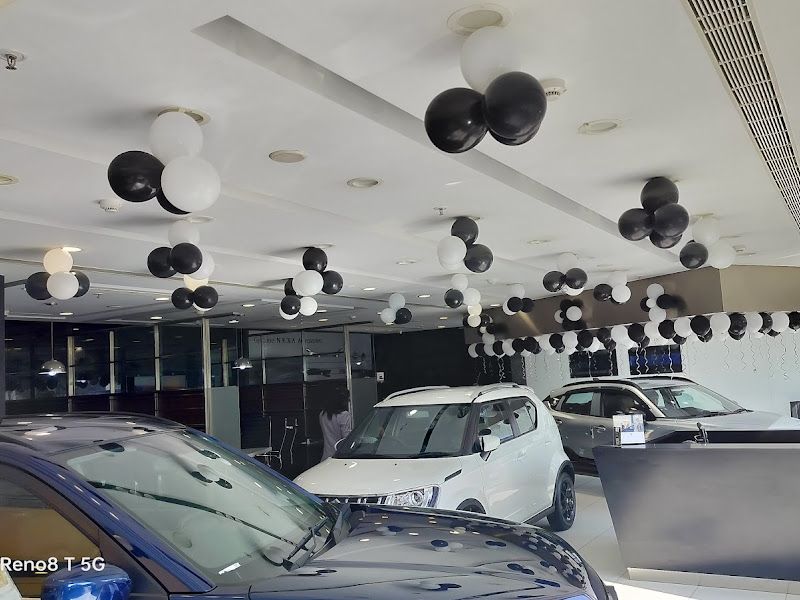 Car-showroom ceiling decor — black and white balloon clusters strung across a dealership floor for a corporate event — Arya Events Planner, Kharghar, Navi Mumbai