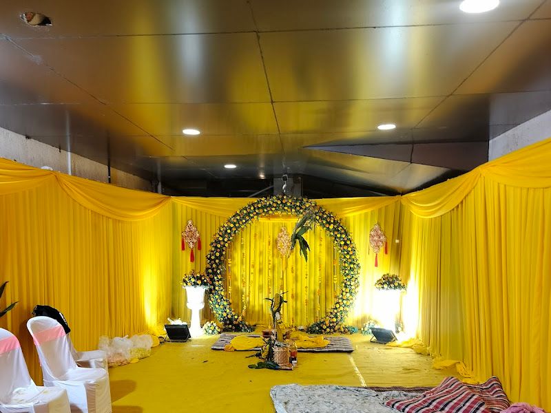 Haldi setup in a hall — bright yellow drapes with a circular floral ring backdrop and white seating — Arya Events Planner, Kharghar, Navi Mumbai