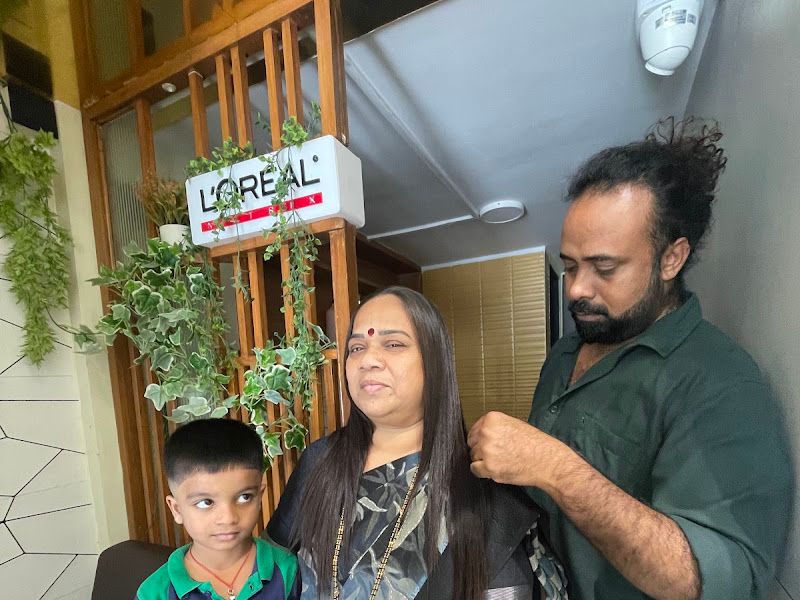 Stylist draping a saree for a female client (with her child alongside) under the L'Oréal interior sign — styling/grooming service in action. — The Rush Family Salon, Airoli, Navi Mumbai