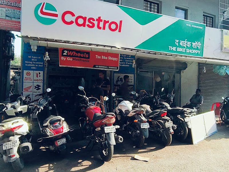 Wide daylight shot of the shopfront with Castrol + The Bike Shoppy signage and customer bikes parked outside — The Bike Shoppy, Vashi, Navi Mumbai