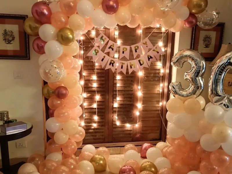 30th-birthday home decor — rose-gold, white and cream balloon arch around a window with fairy lights and a foil '30' — Arya Events Planner, Kharghar, Navi Mumbai