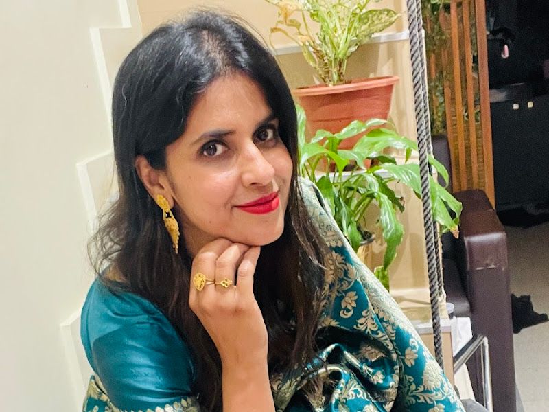 Client in a teal Banarasi saree seated on the swing prop with greenery and a 'L'OréAL' wall sign behind — shows the salon's photo-friendly interior styling. — The Rush Family Salon, Airoli, Navi Mumbai