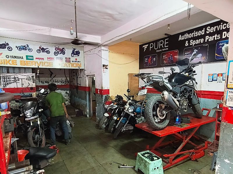 Wide interior view — hydraulic service ramp, authorised service & spare parts dealer boards, bikes in for service — The Bike Shoppy, Vashi, Navi Mumbai
