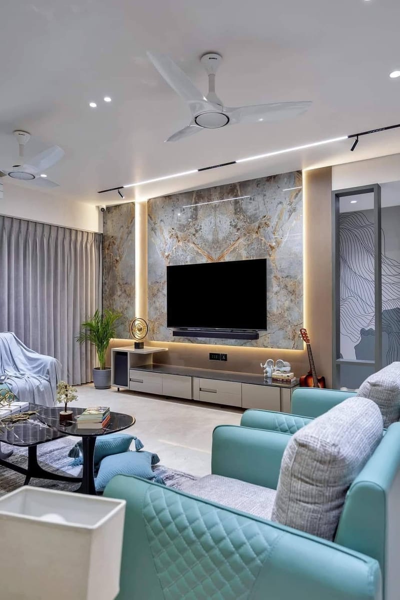 Living room with turquoise sofas, television, marble accent wall and ceiling fans
