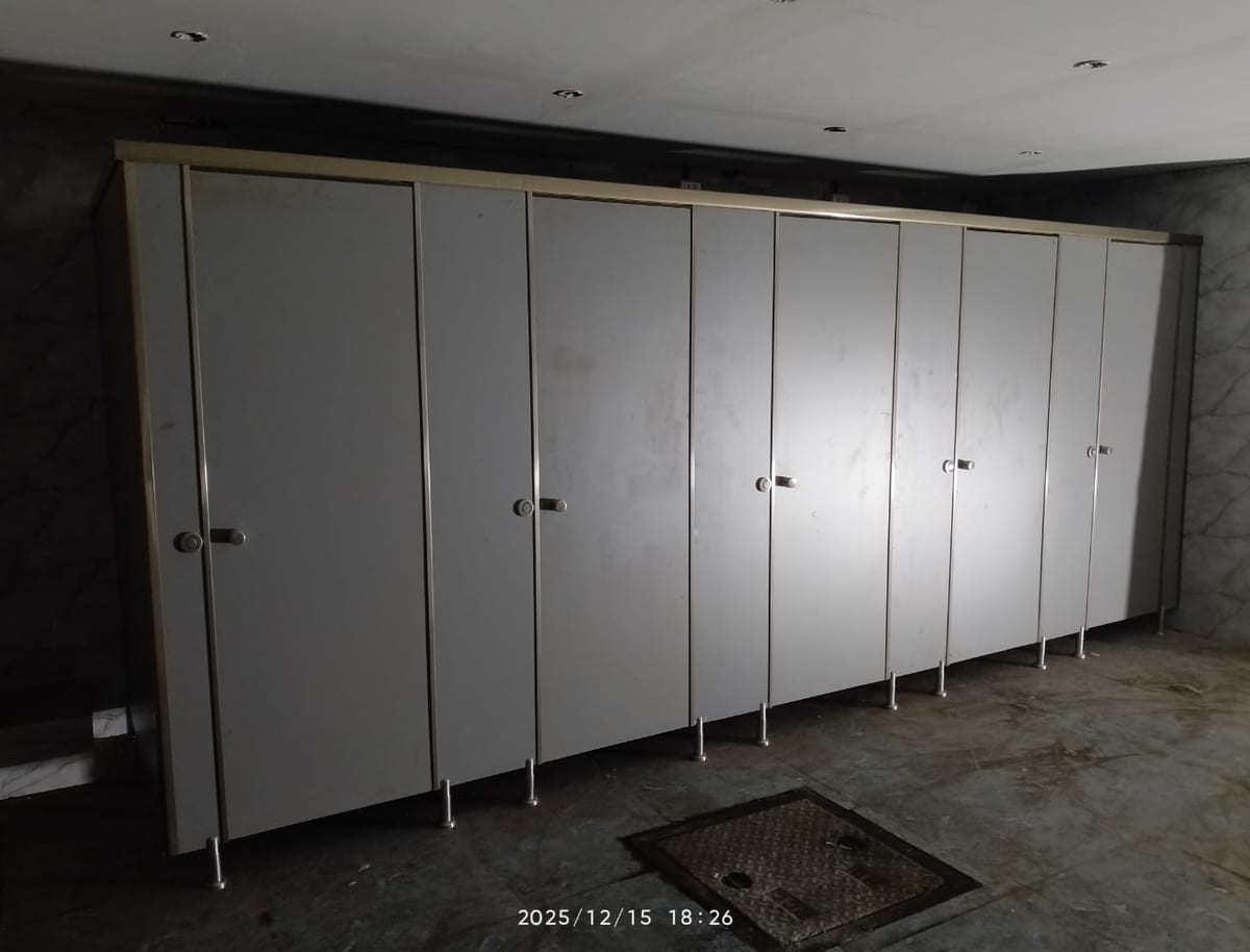Row of white partitioned restroom stalls inside a tiled room