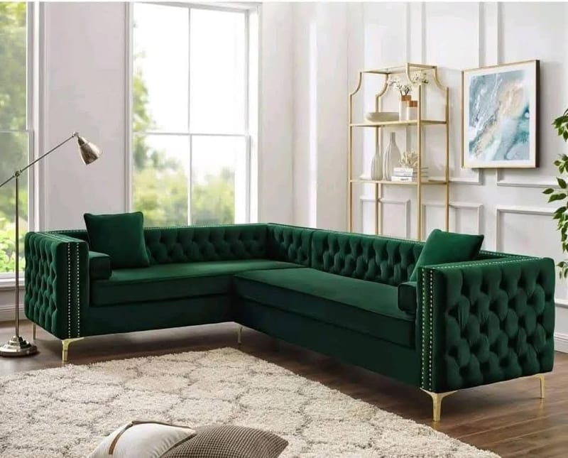 Dark green tufted sectional sofa with gold legs in a bright living room